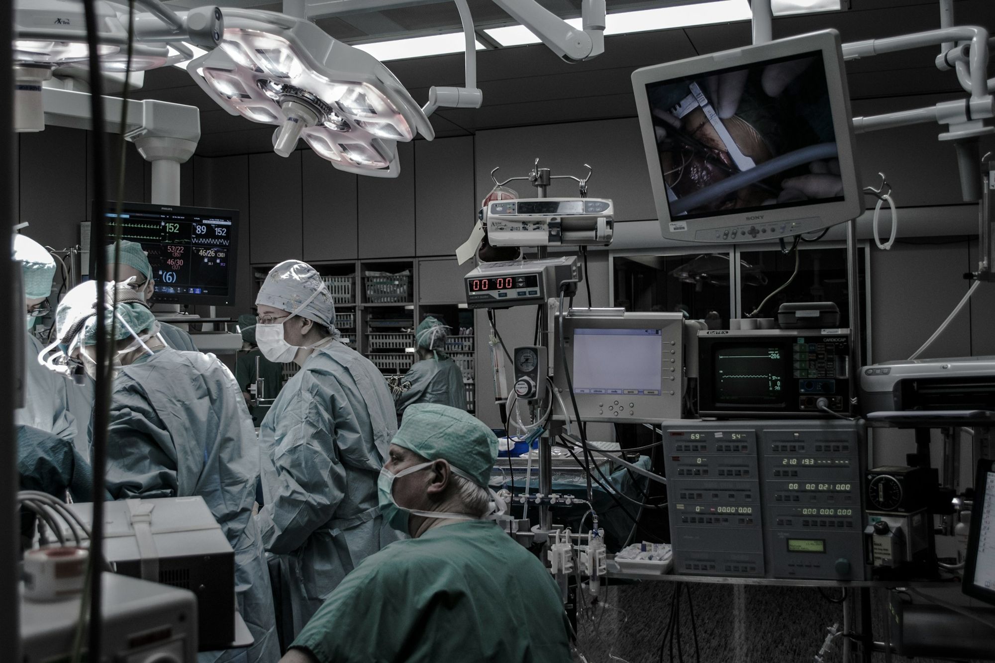 A surgical team at work in an operating room under surgical lights and monitors