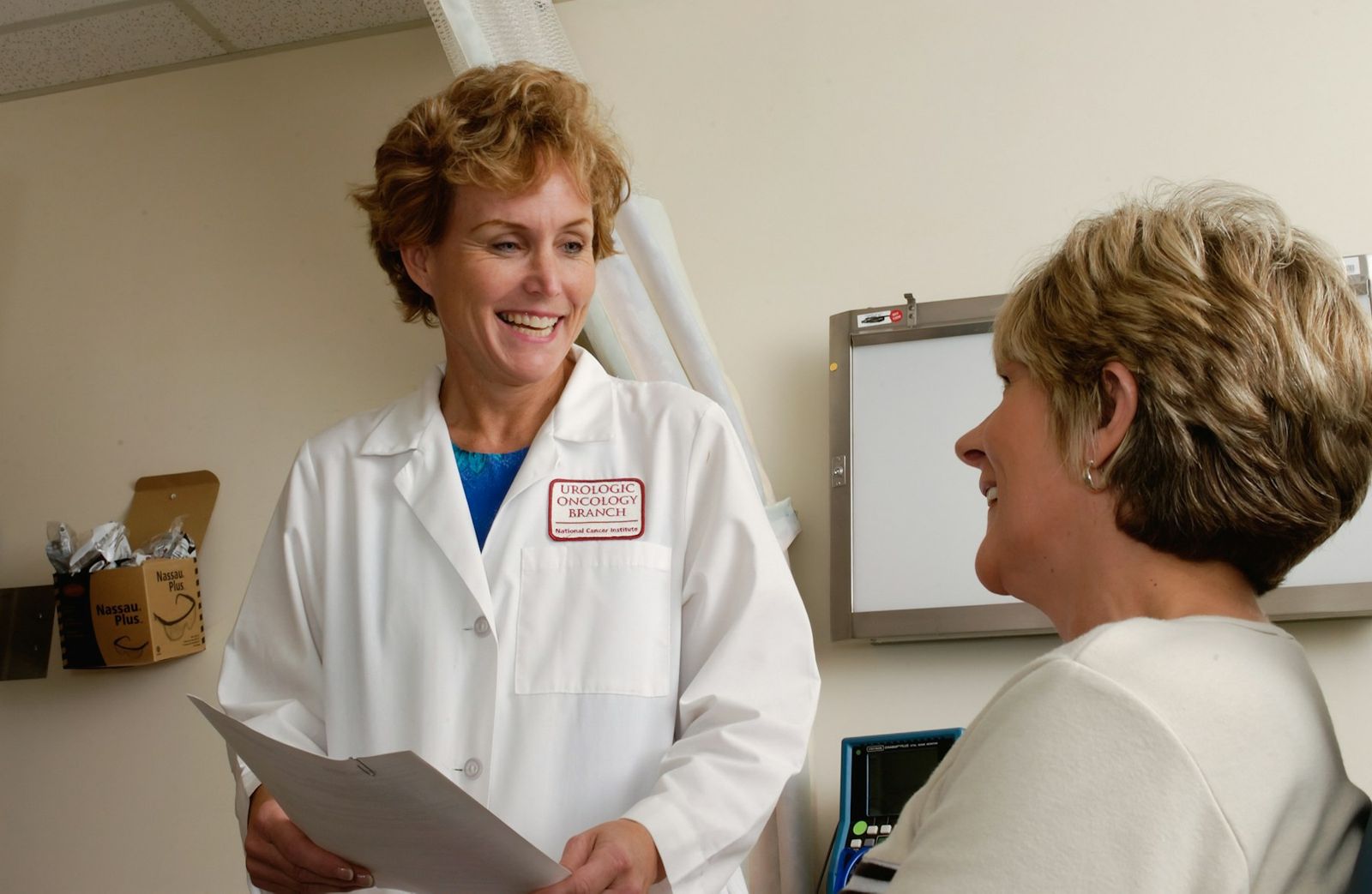 A doctor in a white coat talking with a smiling patient